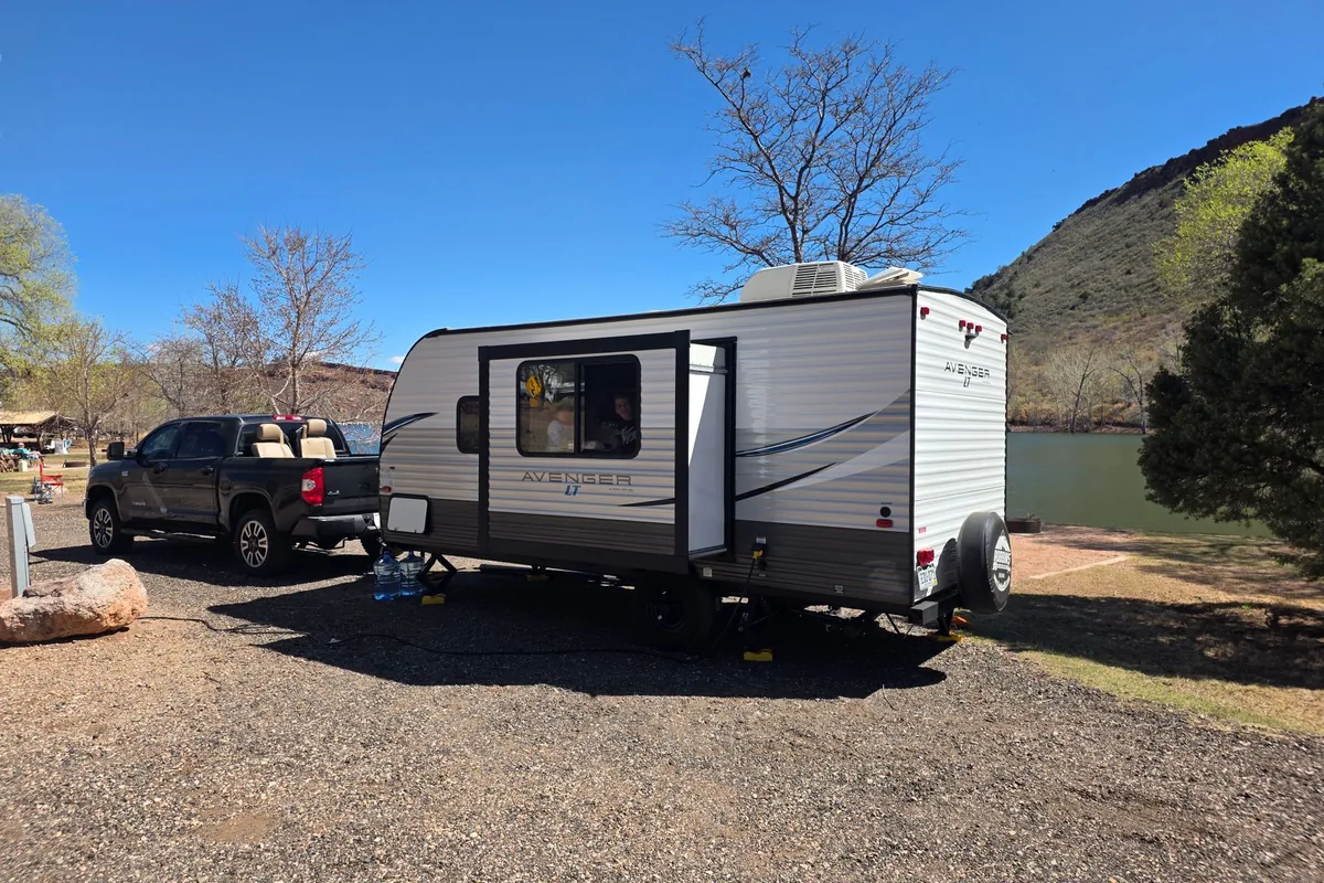 A truck and travel trailer set up at a lakeside campsite