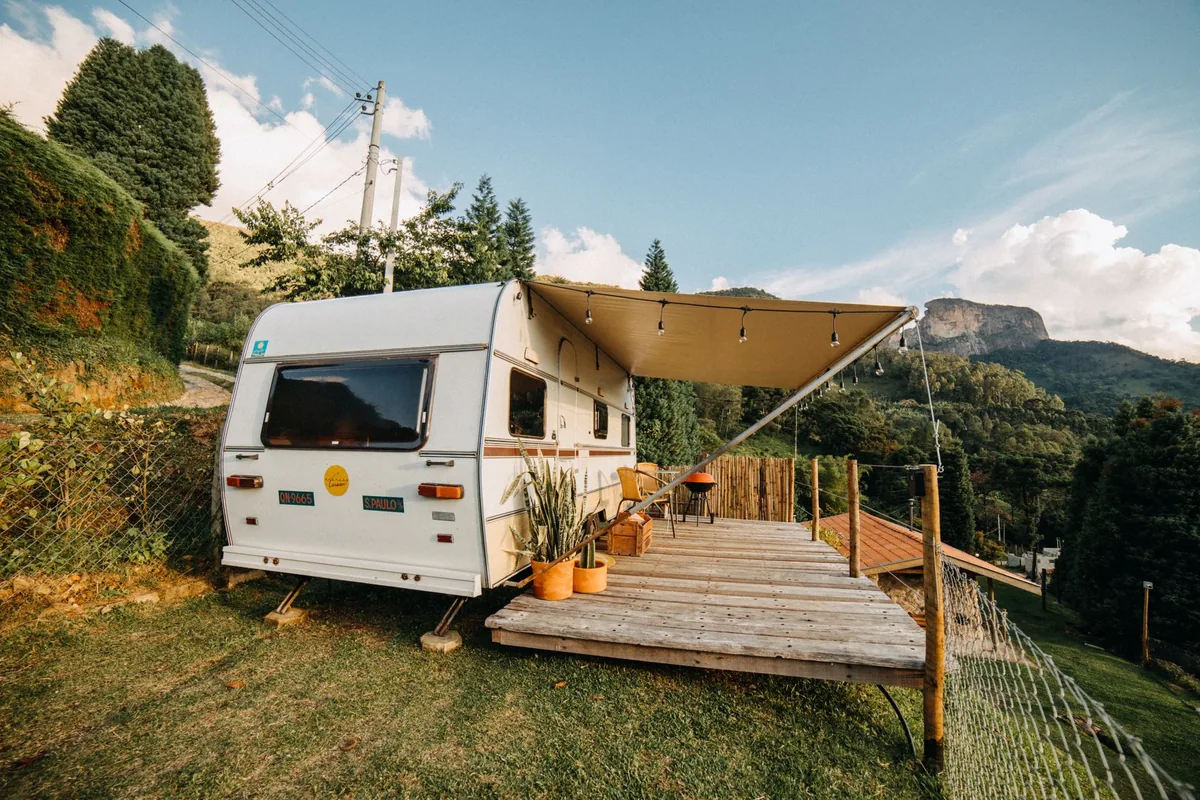 A travel trailer with its awning extended over a wooden deck in the hills